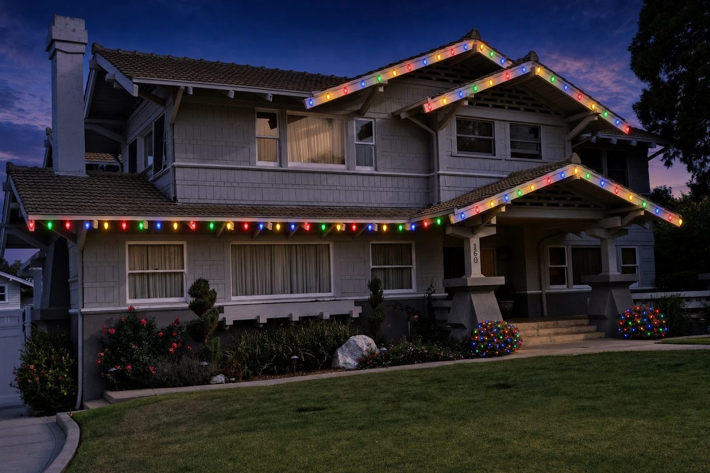 The same craftsman home rendered with multicolor roofline lights and wrapped shrubs